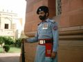 Guard at the mausoleum, with Lahore Fort in background