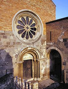 Detail of a stone church with a rose window and a decorated gate