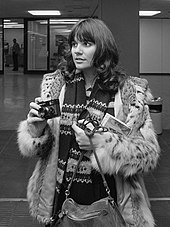Black-and-white image of a 30-year-old woman holding a camera
