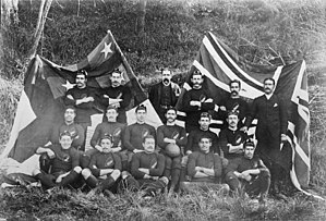 Photo of team players and management all of whom are seated or standing, in three rows, wearing either their playing jerseys with caps, or formal wear.