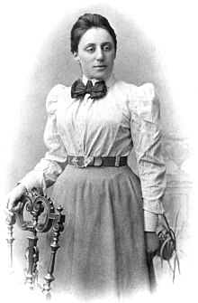 Portrait of Emmy Noether in her 20s with her hand resting on a chair