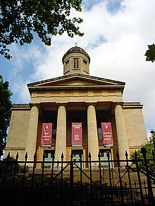 The entrance face of a church in Neoclassical style, with four columns supporting a pediment, over which is a cupola.