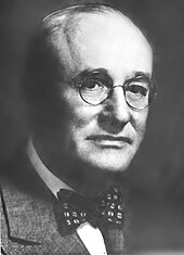 A formally-dressed man with glasses
