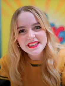 McKenna Grace smiling while wearing a yellow shirt at the 2023 German Comic Con, in Dortmund