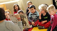 Woman reading picture book to children