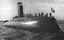 Black-and-white photograph of a submarine on the surface with sailors outside at sea