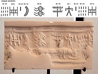 A modern impression of an Indus cylinder seal discovered in Susa, in strata dated to 2600-1700 BCE. Elongated buffalo with line of standard Indus script signs. Tell of the Susa acropolis. Louvre Museum, reference Sb 2425.[68][69] Indus script numbering convention per Asko Parpola.[70][71]