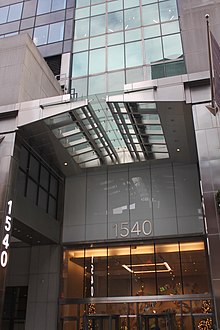 Entrance to the office lobby, with a transom window above the doors and a steel canopy in front of the doorway