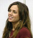 Eliza Dushku smiling at a convention, wearing a maroon top