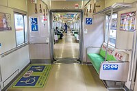 Innenraum eines durchgängigen Zuges der Baureihe 2000 der U-Bahn Fukuoka mit Mehrzweckfläche für Rollstühle und Kinderwagen und priority seats