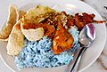 Nasi kerabu served with various herbs, fish meat-stuffed pepper, salted egg, fried fish, keropok and marinated chicken.