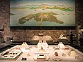 Modell des zuletzt 1487 erweiterten Haupttempels von Tenochtitlan und Luftbild der inmitten eines Sees gelegenen Stadt.