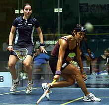 A teammate in a dark blue uniform jumps up while David passes the ball to her.