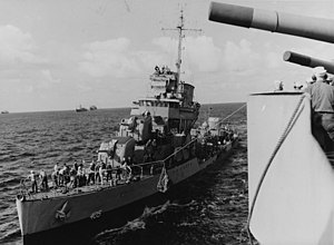 The USS Rowan receiving provisions via "high-line" from USS Augusta (CA-31) while operating at sea, 4 December 1942.