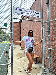 Reese standing at the entrance of an outdoor basketball court named the "Angel Reese Court"