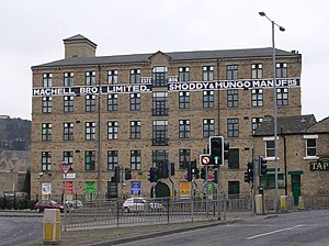 Five story building with many high windows stretching across the background with road and traffic light controlled junction in front