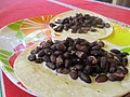 Cooked whole black turtle beans on tortillas