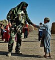Lieutenant R. Gutierrez from A Co, 1st Bn, 7th SFG(A) gives an Afghan boy a coloring book in Kandahar Province during a meeting with local leaders, September 2008