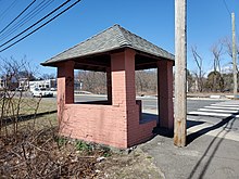 A small brick waiting shelter at the side of a road