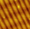 The characteristic reconstruction fringes on the (100) surface of gold are 1.44 nanometers wide[20] and consist of six atomic rows that sit on top of five rows of the crystal bulk. Image size is approximately 10 nm by 10 nm.