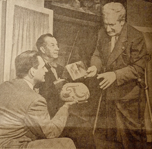 Three men demonstrate the Aztec hoax claims using an inverted bowl to represent Earth and a copy of Frank Scully's book to represent a magnetism-powered flying saucer.