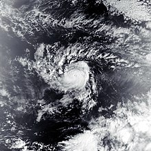 A visible satellite image of a very compact tropical storm, with a small and partially obscured eye in the center of its central dense overcast