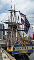 The frigate Hermione moored in New York in 2015, flying the Betsy Ross flag and the Serapis flag, two early US flags and ensigns.