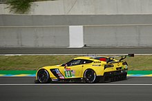 A side photograph of a yellow Chevrolet Corvette C7.R with the number 64 inside a lime green square