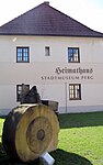 Nordansicht des Heimathaus-Stadtmuseums Perg mit Mühlstein aus Sandstein im Vordergrund