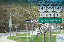 A sign assembly indicates that NY 343 westbound is accessed by turning left while NY 22 northbound and NY 343 eastbound are straight ahead. A sign below the route shields indicates that Millbrook is located eight miles to the west on NY 343.