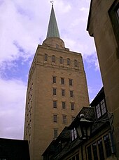 A large square tower with regular rows of three windows, topped by a small metal spire