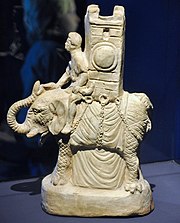 A small, white statuette of an elephant with a mahout