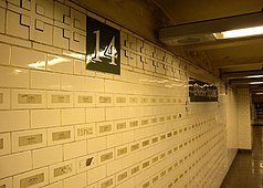 A wall of white tiles on the station's mezzanine. Stickers with the names of 9/11 victims are placed on the tiles.