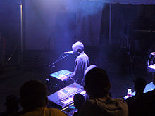 A man with electronic musical instruments performing at an annual electronic dance music event.