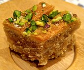 Photo of baklava on wooden dish, garnished with pistachios