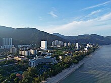 Aerial view of a beach in the city, flanked by buildings and hills forming the backdrop.