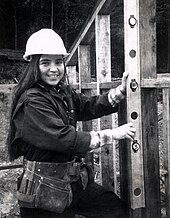 A woman in a hard hat near wooden beams