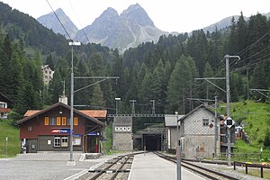 Two-story building with gabled roof next to double-track railway line entering a tunnel