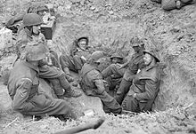 A group of soldiers relax in a defensive position they have dug
