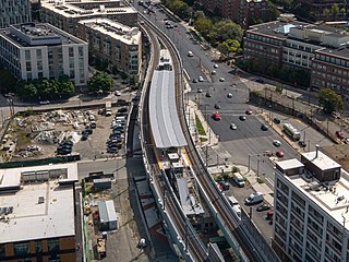 An aerial view of an elevated railway station under construction in an urban area