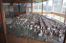 A large table enclosed in glass containing many miniaturized buildings laid out to form a town