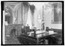 the Wilson desk sitting in front of an ornate fireplace and mirror.
