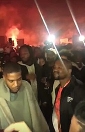 The two members of Kids See Ghosts stood infront of a bonfire