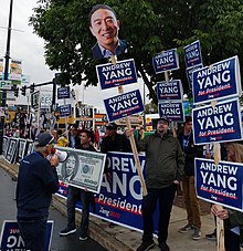 Supporters of Yang's campaign raising signs that say "Andrew Yang for President".
