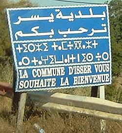 Trilingual welcome sign in Isser written in Arabic, Kabyle (Tifinagh script), and French. ("The municipality of Isser welcomes you.")