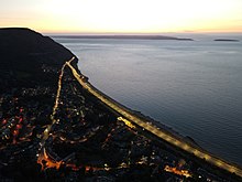 This view of Penmaenmawr at sunset shows how the modern A55 Expressway bypasses the older road through the town centre before resuming the original route around the headland.