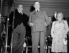 A photo of two men and a woman standing on a stage