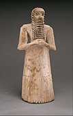 Standing male worshiper, one of the twelve statues in the Tell Asmar Hoard; 2900–2600 BC; gypsum alabaster, shell, black limestone and bitumen; 29.5 x 12.9 x 10 cm; Metropolitan Museum of Art