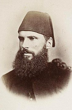 Formal photo of a young, bearded man in a fez