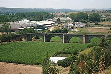 Coria old bridge. The river has changed course, and no longer flows beneath the bridge. Instead there are fields of green crops